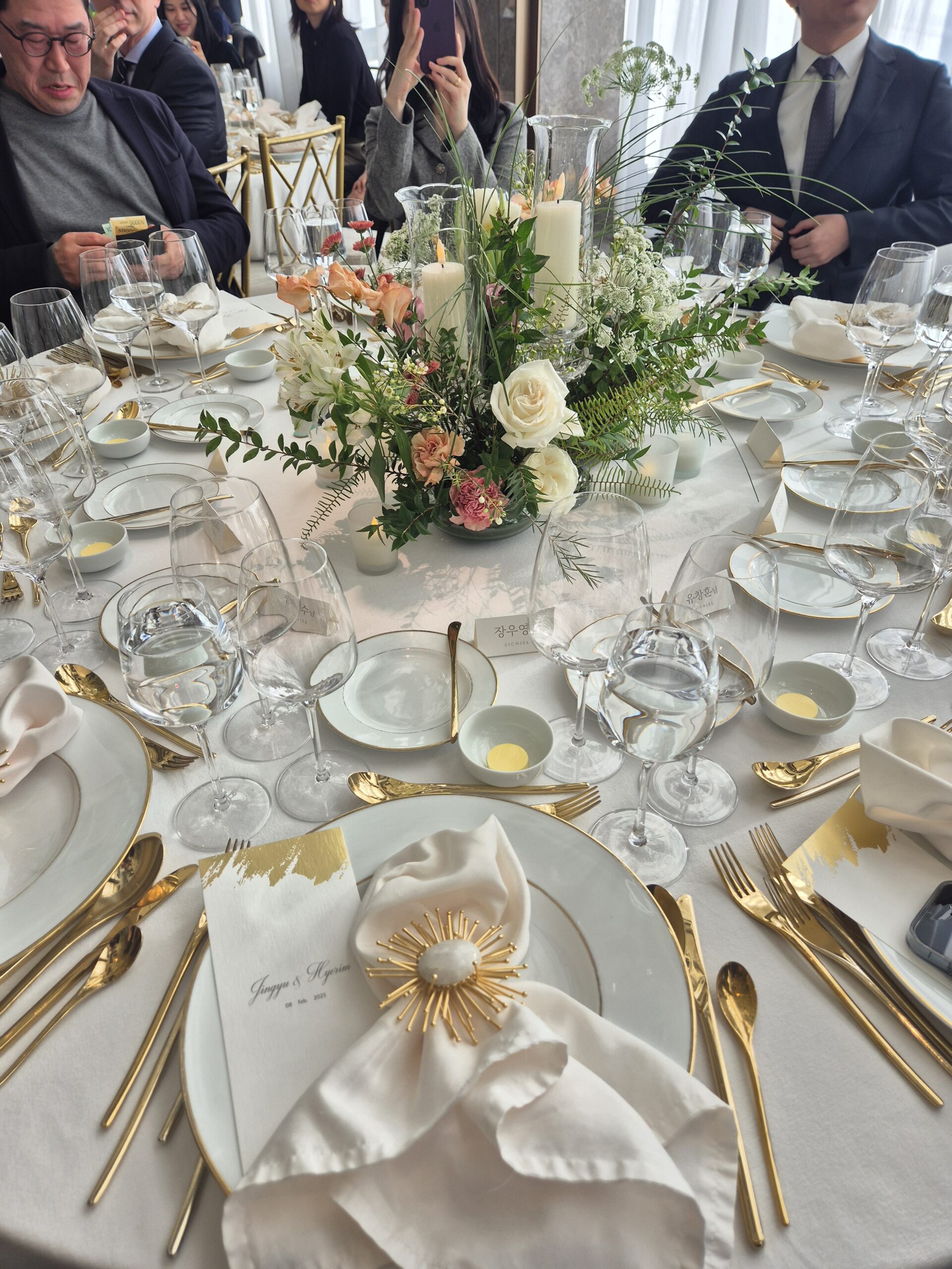 Korean hotel wedding round table with golden cutlery white roses and name cards