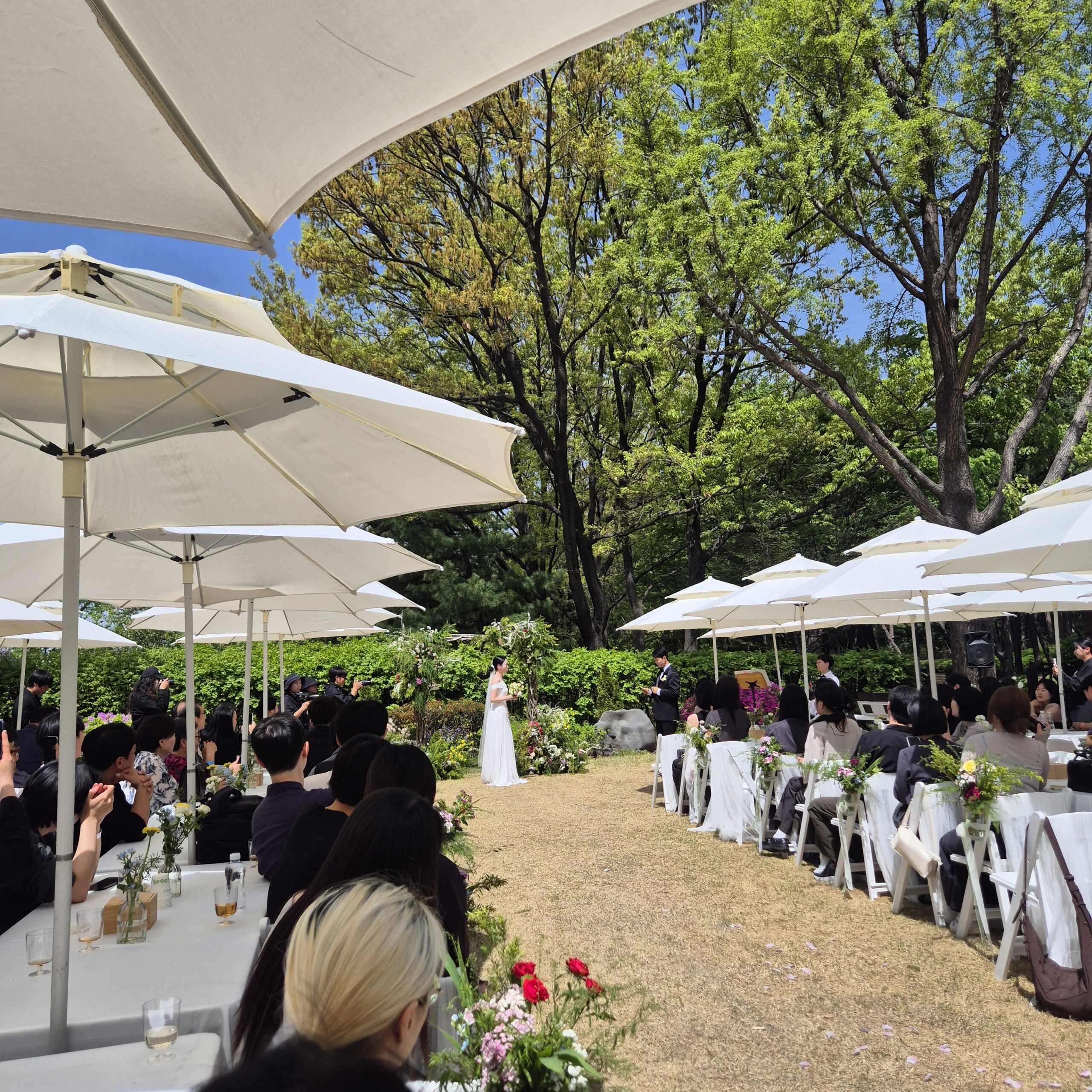 Outdoor Korean wedding ceremony with white parasols and garden setting Seoul