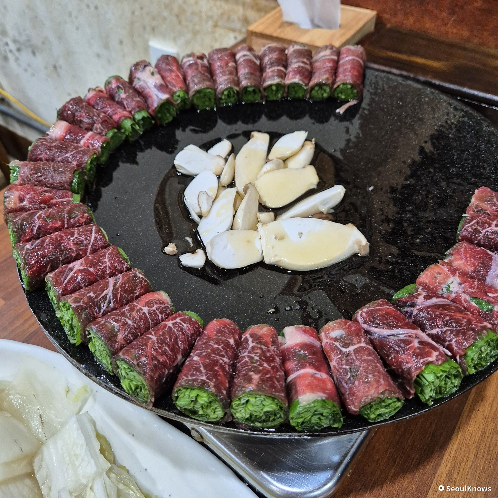 Beef rolls arranged around the dome grill with mushrooms at Asura