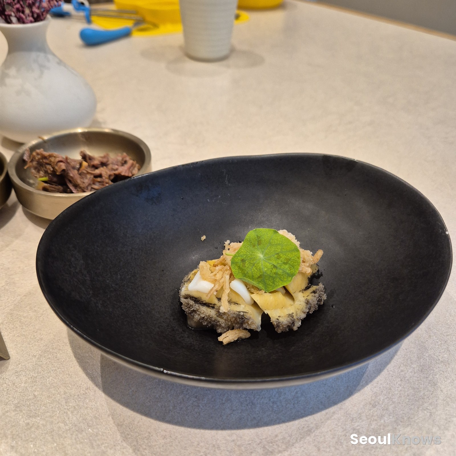 Steamed Wando abalone with cuttlefish in a black bowl