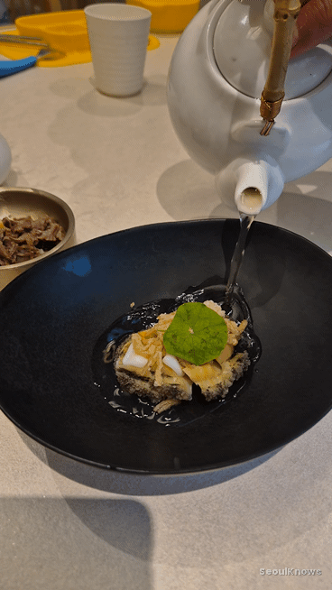Staff pouring shrimp broth over the steamed abalone at Donghwa Gook
