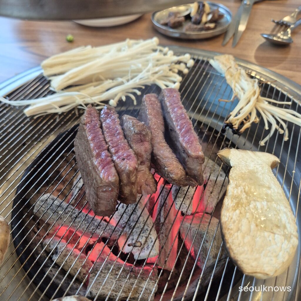 Hanwoo Korean beef grilling over charcoal at a Korean BBQ restaurant