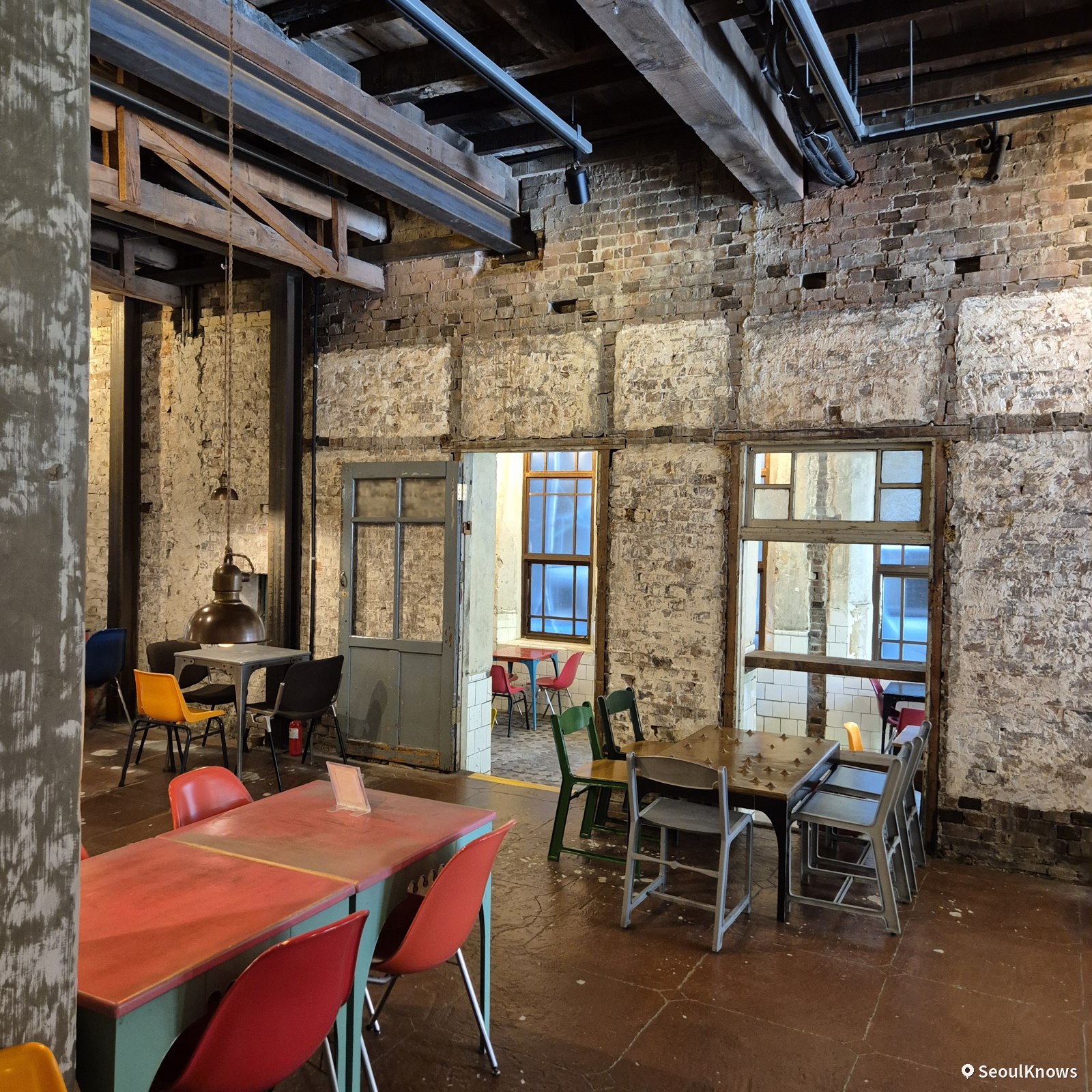 Vintage interior of Brown Hands Baekje with exposed brick walls and colorful chairs