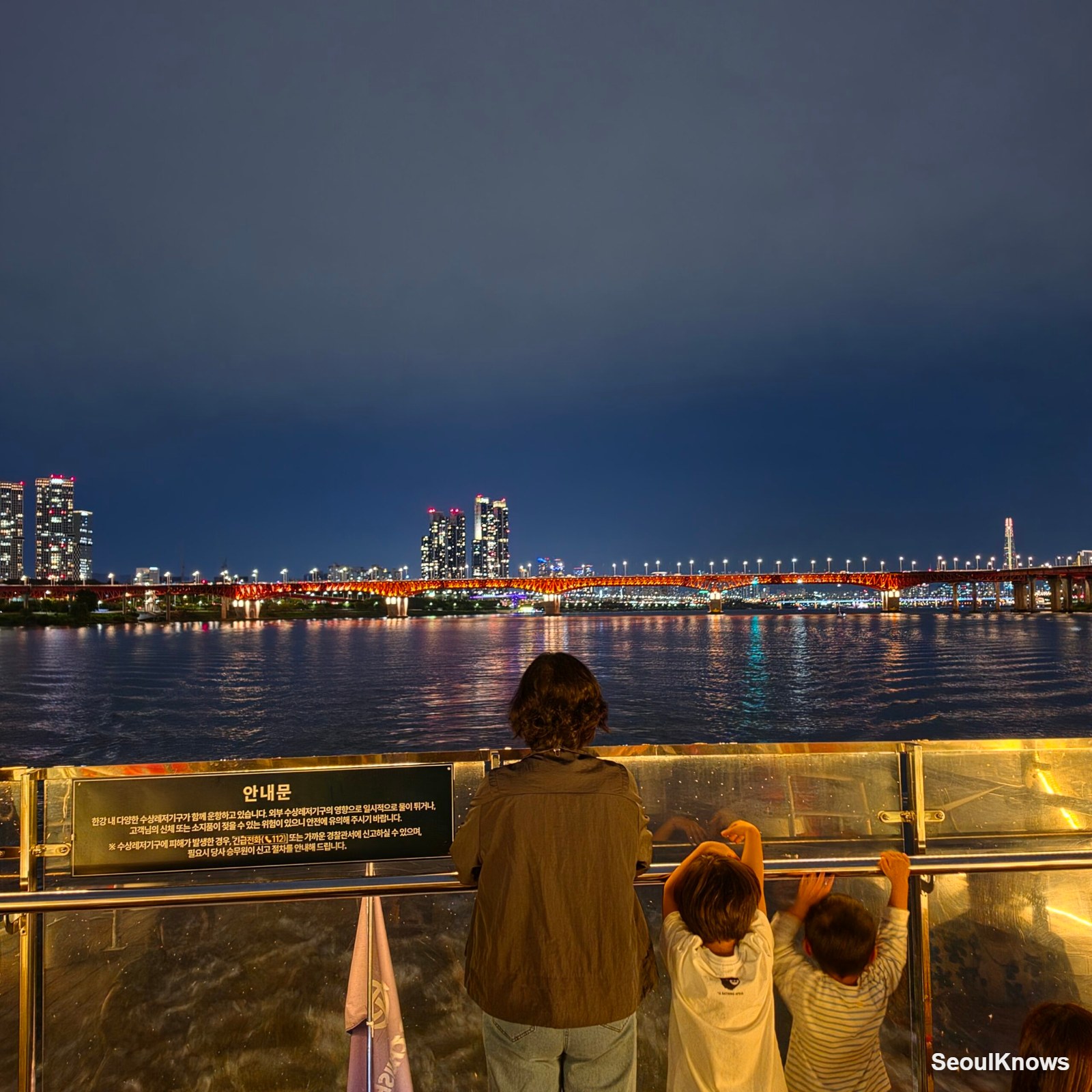 Children watching the Seoul skyline from the deck of a Han River cruise