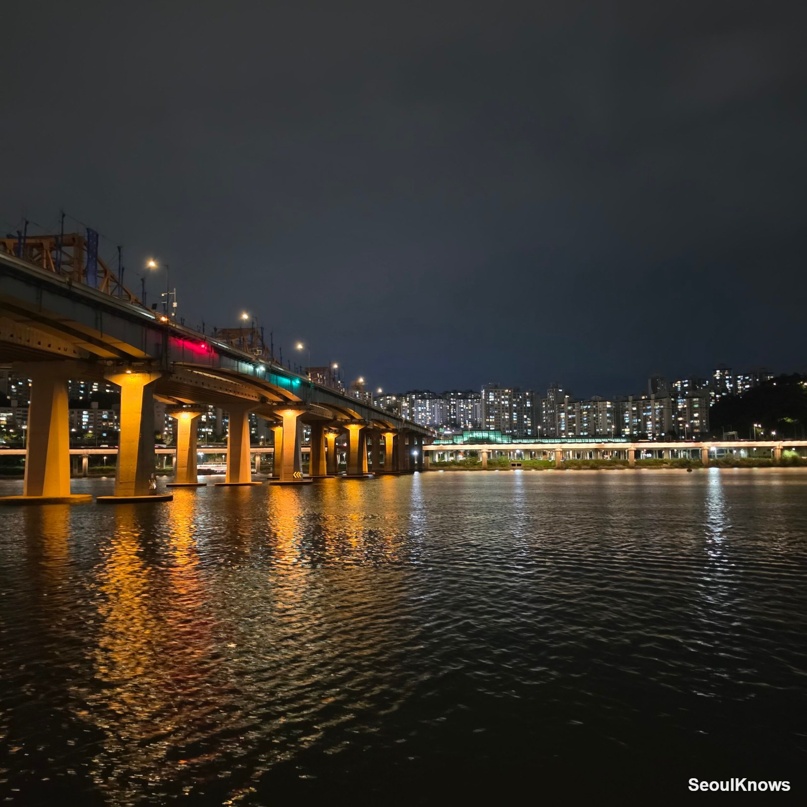 Han River bridge lights and apartment towers seen from the water at night