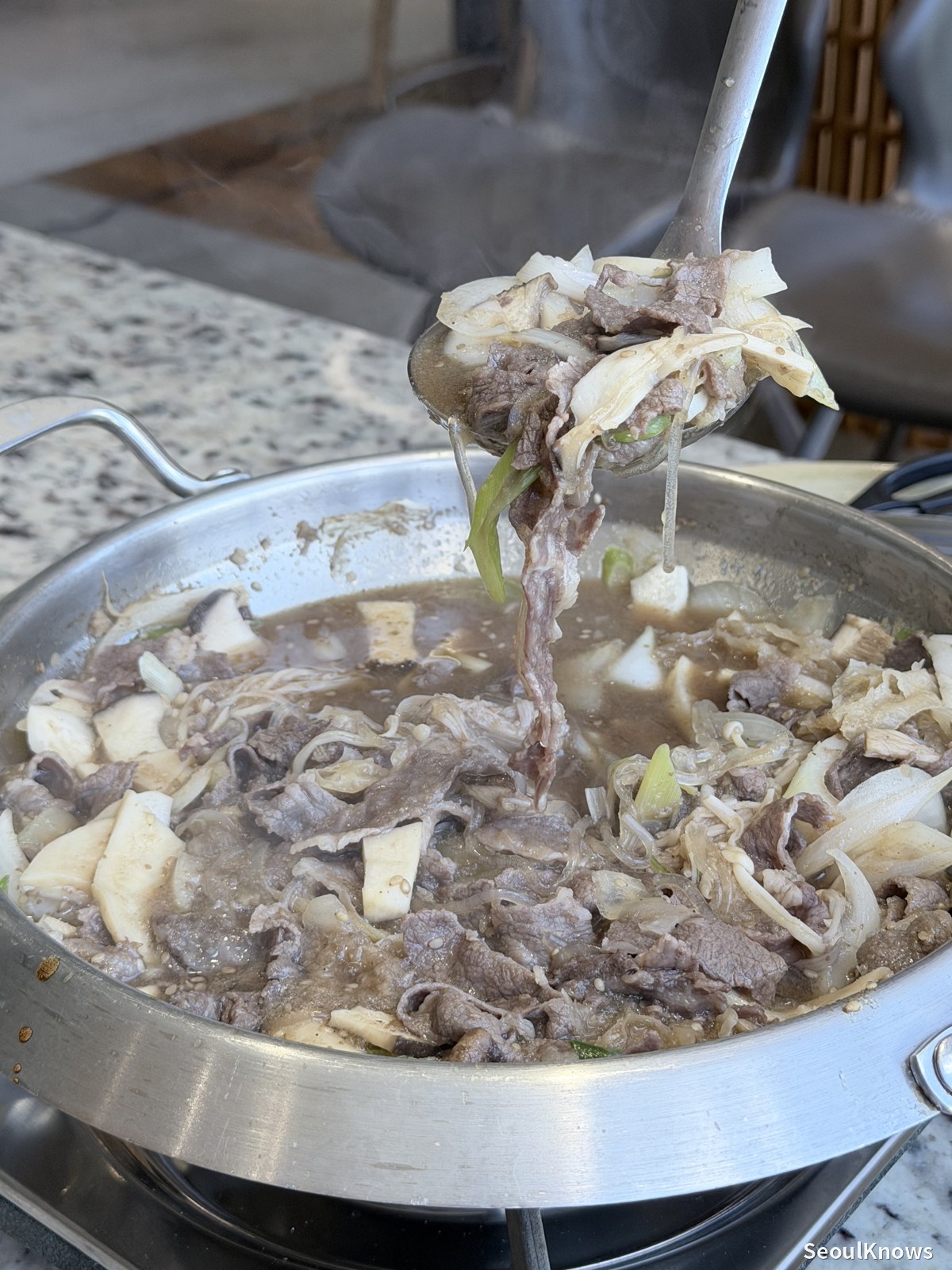 Hanwoo bulgogi cooking in broth with mushrooms and onion
