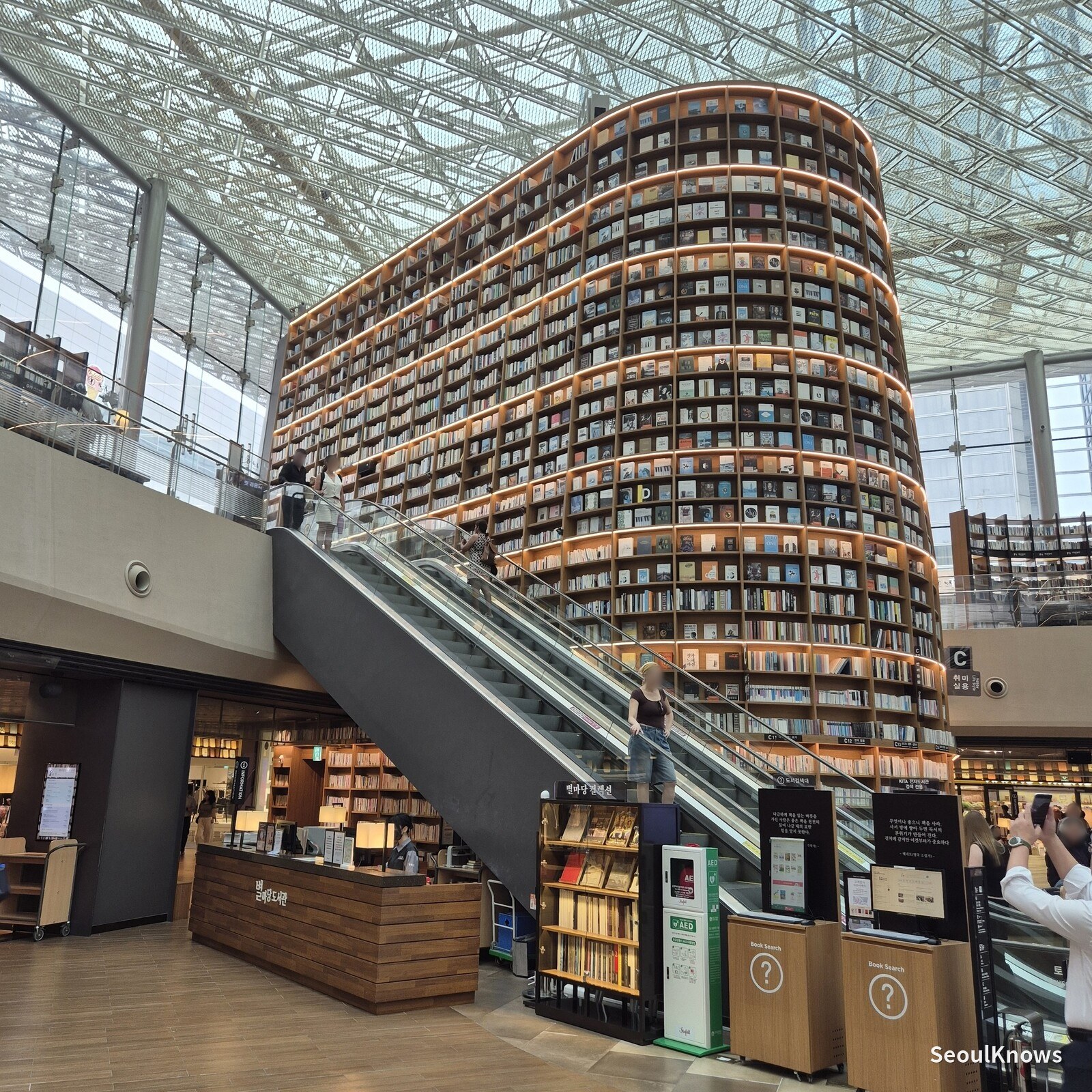 Starfield Library shelf tower beside the escalator, real books only on the lower shelves