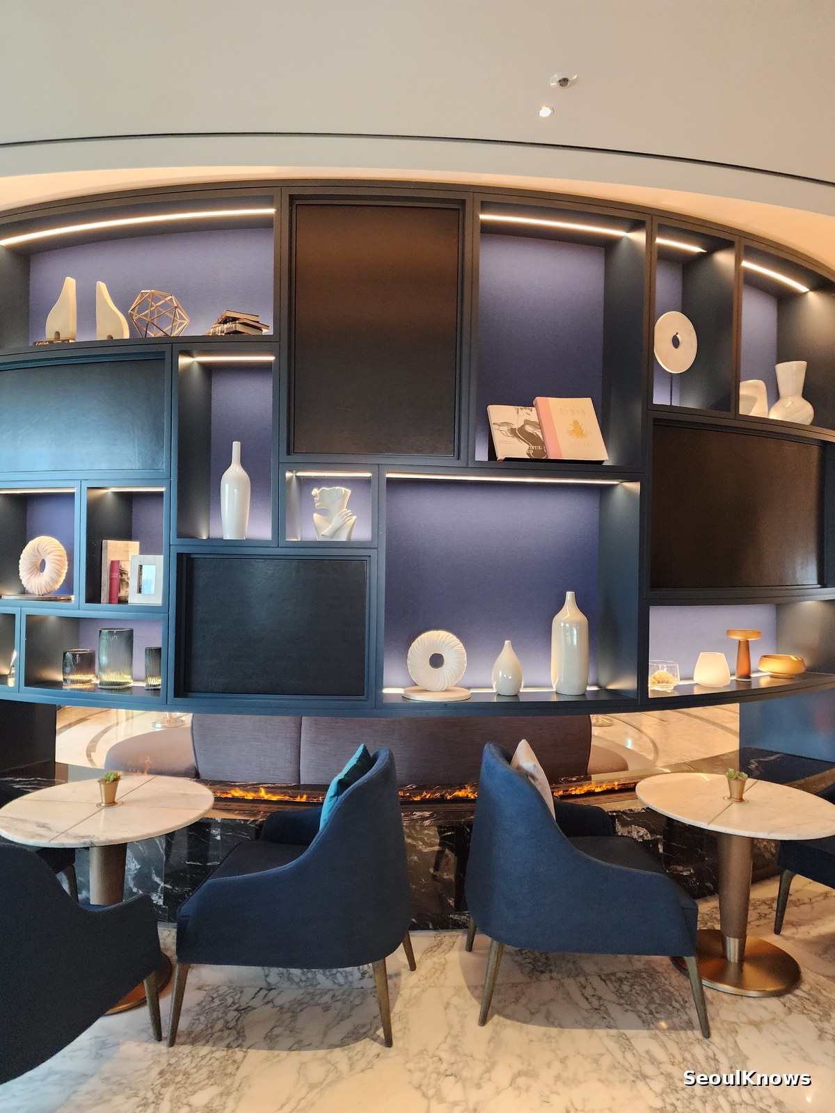 Navy blue armchairs and a curved display cabinet inside L'Espace lounge Seoul