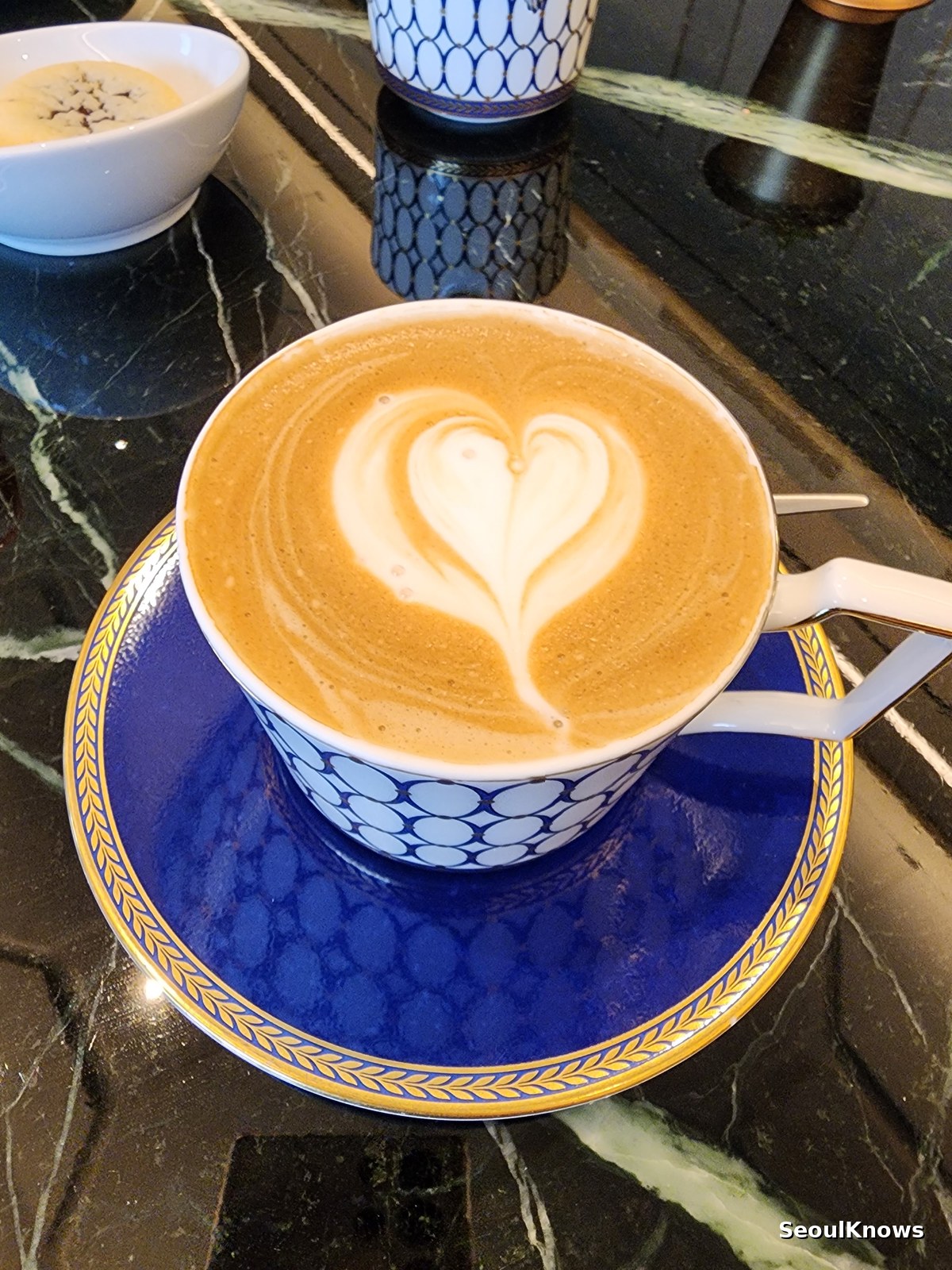 Café latte in a cobalt blue Wedgwood cup on a marble table at L'Espace Seoul